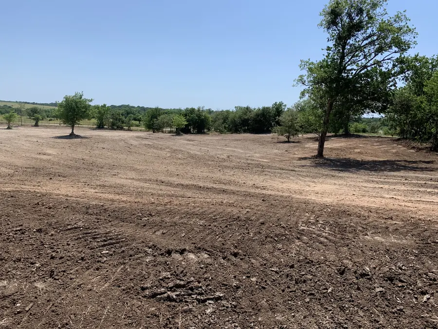 Large cleared field with fresh dirt and a few trees kept