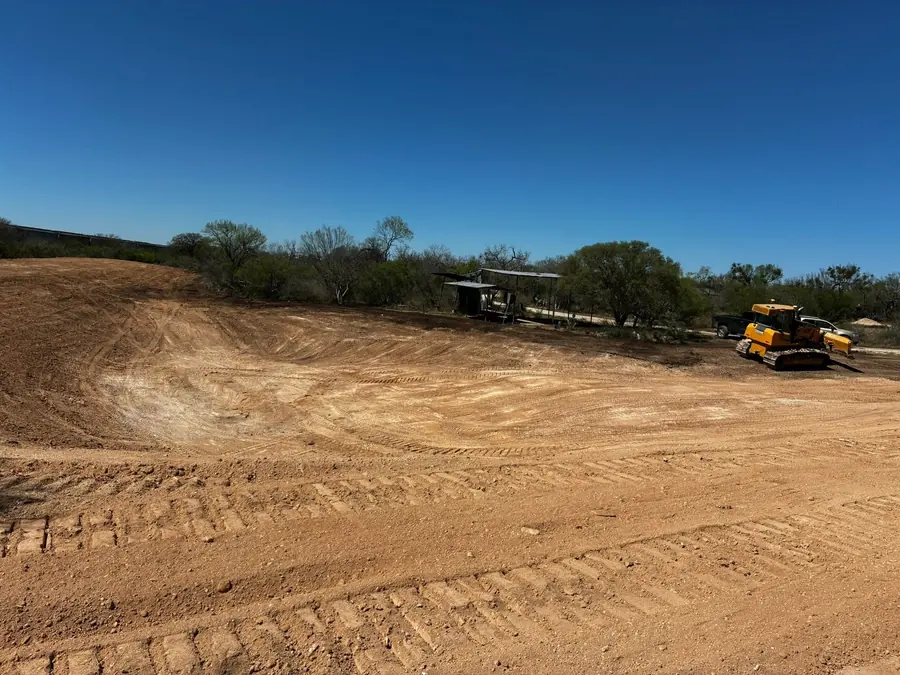 Large graded dirt pad with a dozer parked at the far edge