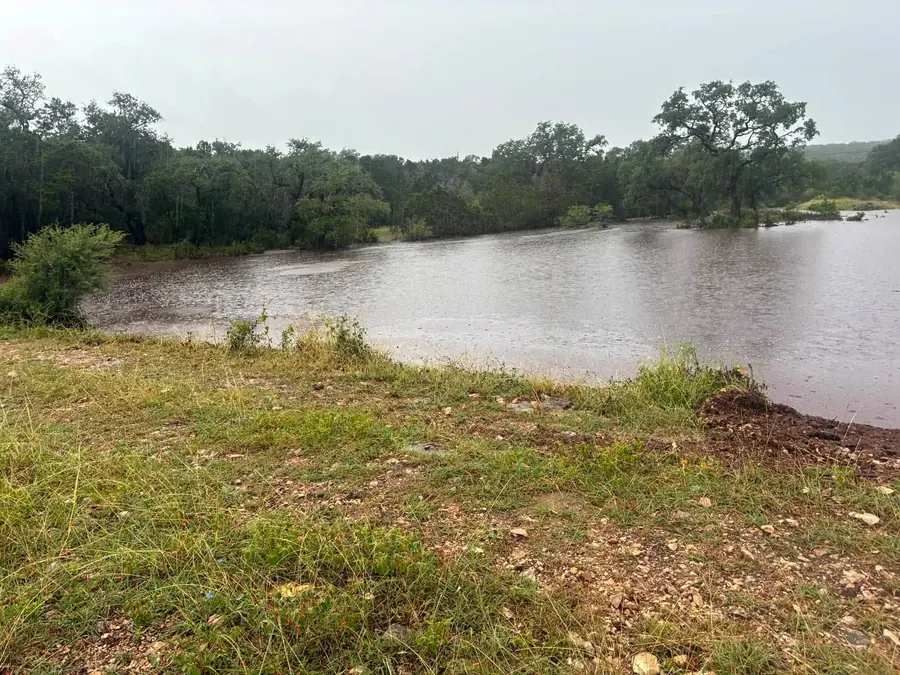 Finished pond full of water with grassy banks and live oaks
